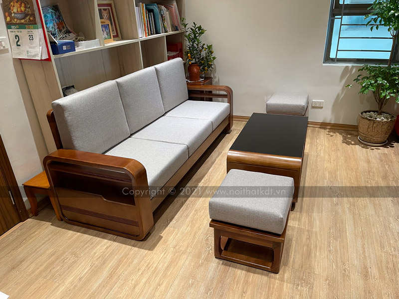 Bộ sofa văng 3 chỗ được kê sát với giá sách gỗ, kết hợp bàn trà hình chữ nhật ở giữa và hai ghế đôn đối xứng, tạo nên không gian tiếp khách nhỏ gọn, ấm cúng (Ảnh thực tế tại nhà khách của Nội thất KDT)