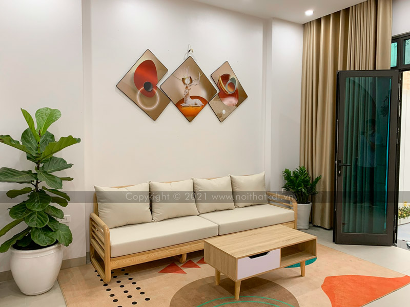 Sofa văng gỗ 4 chỗ được kê sát tường và gần cửa ra vào, đối diện với một bàn trà nhỏ hình chữ nhật nhằm tiết kiệm diện tích và tạo nên không gian tiếp khách gọn gàng, ấm cúng (Ảnh thực tế tại nhà khách của Nội thất KDT)