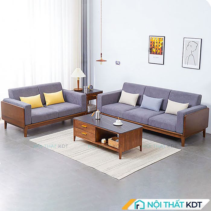 Bộ sofa đôi khung gỗ sồi bọc nỉ xám tím kê vuông góc tạo không gian tiếp khách thân mật và cân đối.